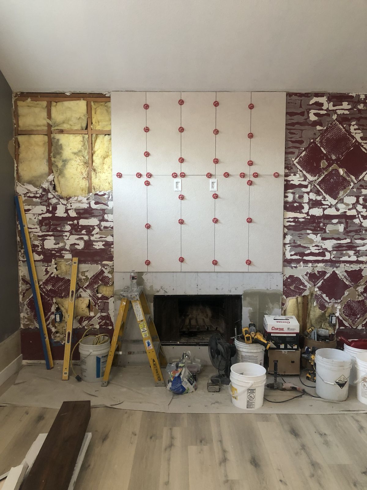 Fireplace wall mid-install with large porcelain panels and leveling clips