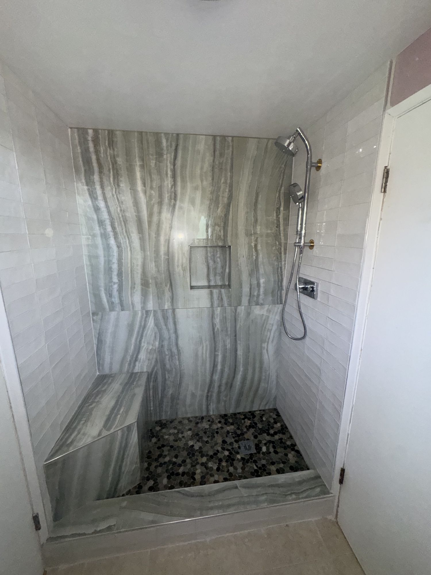 Walk-in shower with onyx-look porcelain, built-in bench and pebble floor
